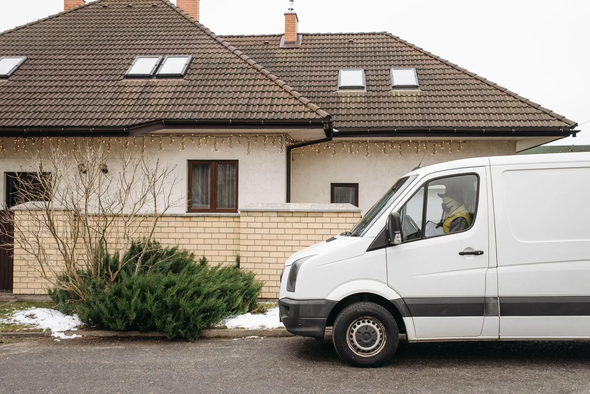 Hvid varebil parkeret foran et parcelhus